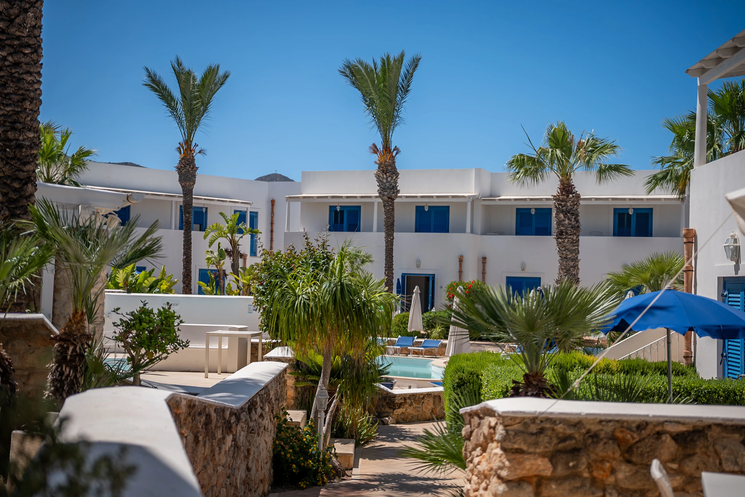 Cortile di Cala La Luna con palme e facciate mediterranee